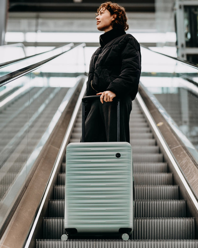 Mintfarbener Koffer auf Rolltreppe im Flughafen – modernes Reisegepäck der Serie Emotion von Karl Noss
